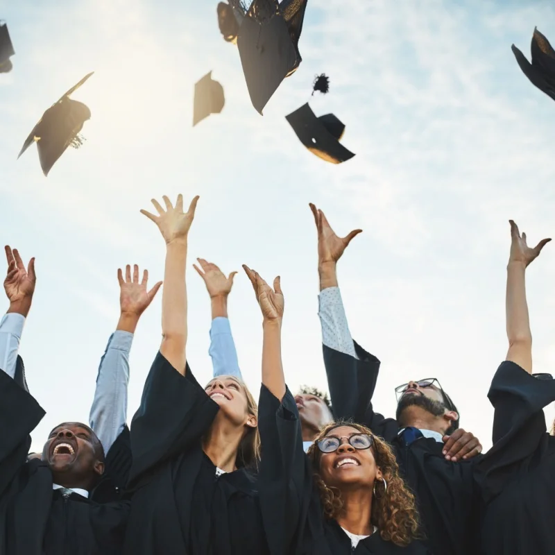 HBL recent graduates throwing their caps into the air